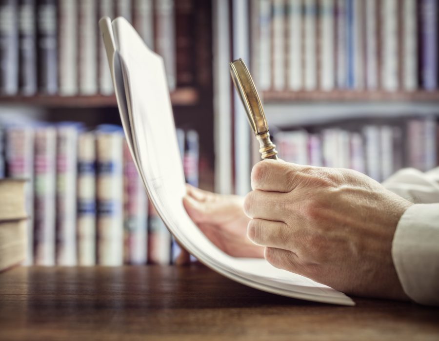 Businessman or attorney with magnifying glass reading documents